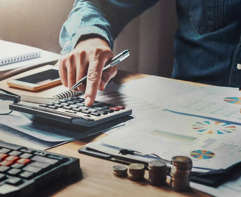 Person calculating finances with documents and coins.