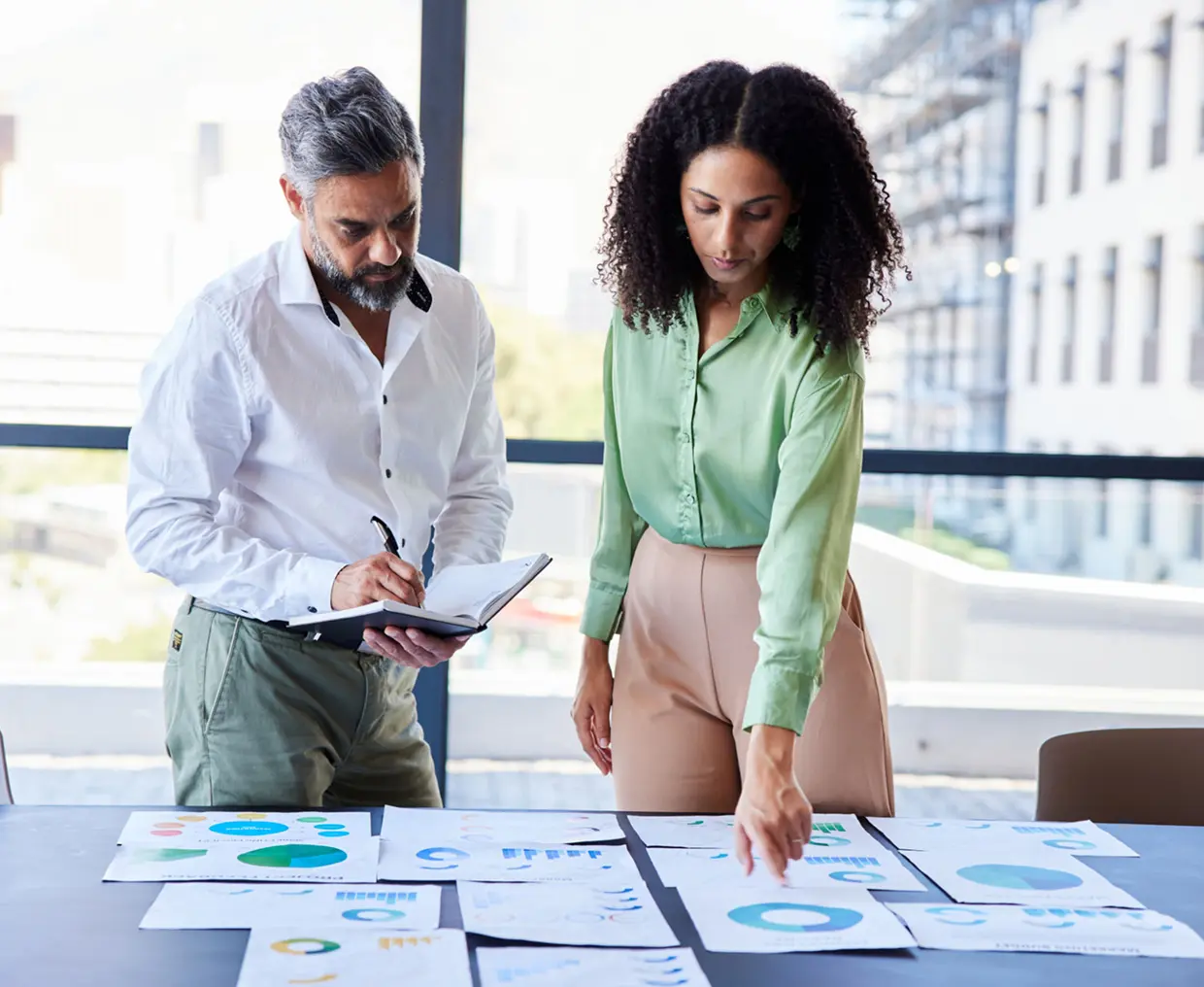 Two colleagues reviewing charts on table.